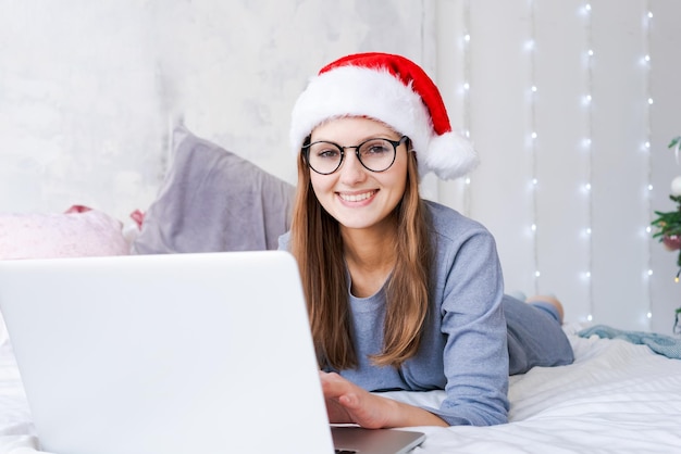 Donna con cappello da Babbo Natale che gioca sul computer portatile durante lo shopping online di Natale per le vacanze