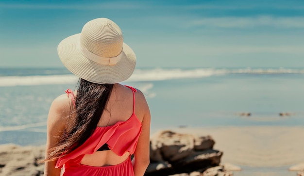 donna con cappello da dietro al mare ragazza che guarda il mare una ragazza con cappello che guarda il mare