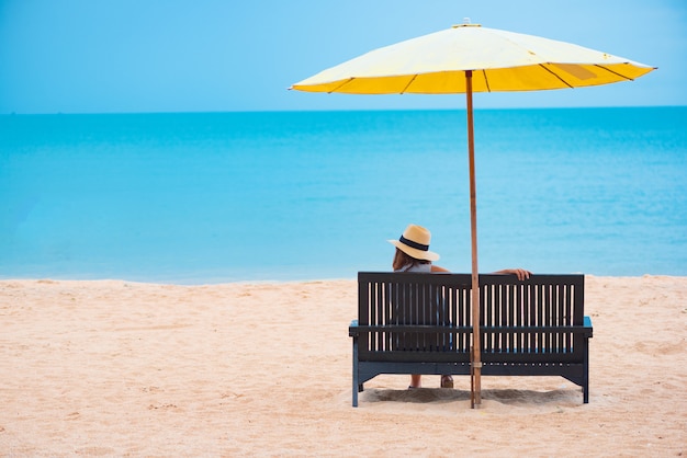 Donna con cappello di paglia rilassante sulla spiaggia.