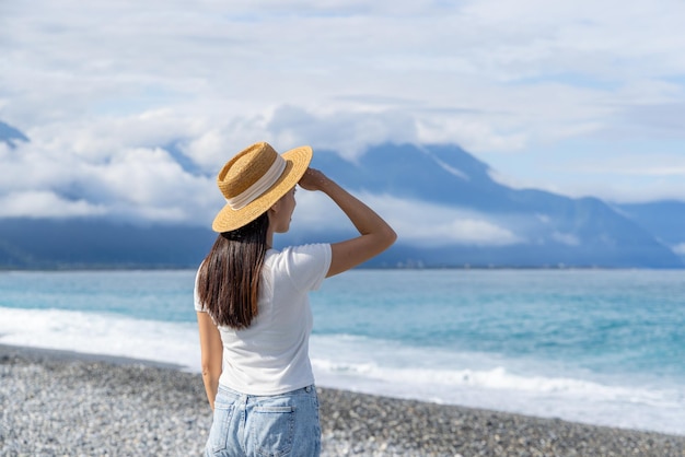 Donna con cappello di paglia sulla spiaggia con cielo blu limpido