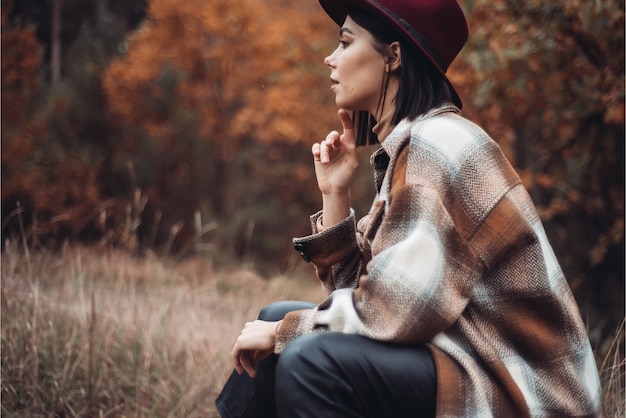 Donna con cappello e cappotto nel bosco