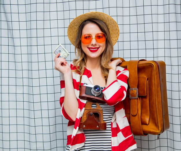 donna con cappello e giacca a righe con macchina fotografica d&#39;epoca, valigia e banconote