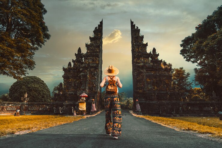 Donna con cappello e zaino entrando nell'ingresso del tempio indù a Bali, Indonesia