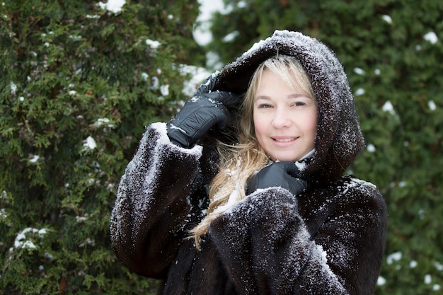 Donna con cappuccio di pelliccia ricoperta di neve