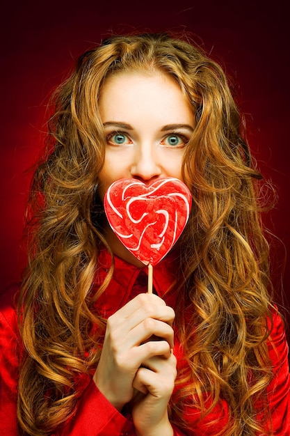 Donna con caramello cuore su sfondo rosso