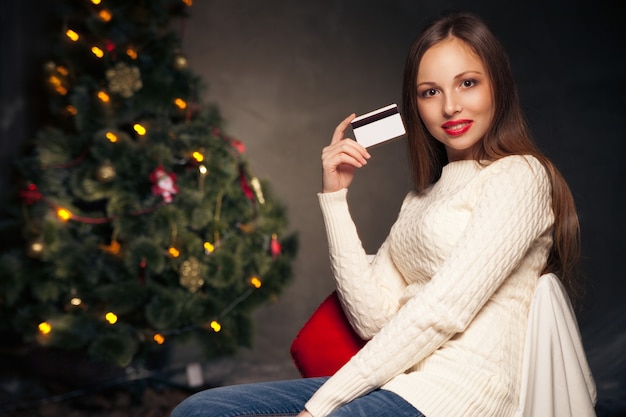 Donna con carta di credito davanti all'albero di Natale