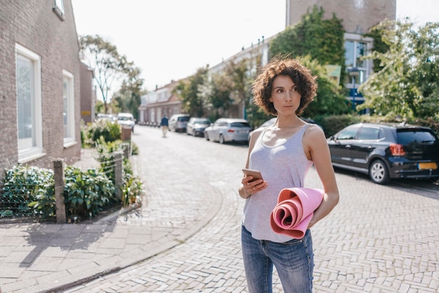 Donna con cellulare e tappetino su una strada