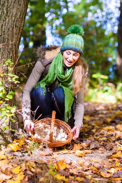 Donna con cesto pieno di champignons nella foresta