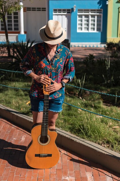 Donna con chitarra in piedi in un parco