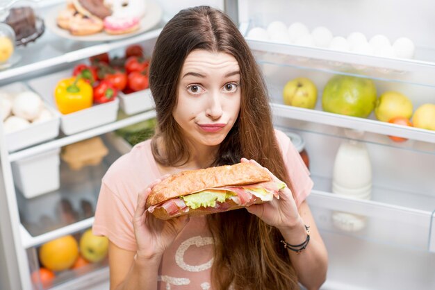 Donna con cibo vicino al frigorifero