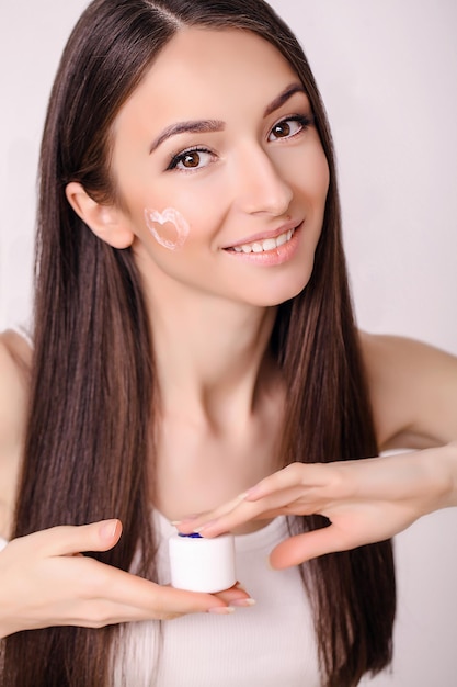 Donna con crema cosmetica su un viso pulito e fresco