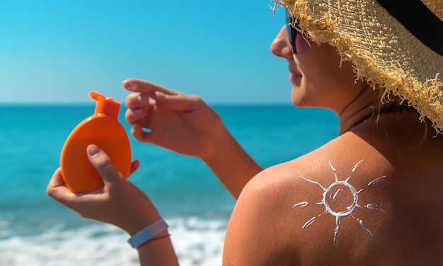 Donna con crema solare sulla schiena. Messa a fuoco selettiva. Mare.