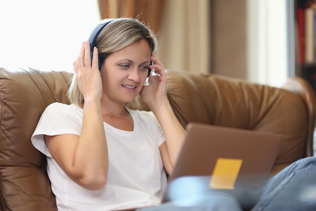 Donna con cuffie e computer che parla online mentre è seduto sul divano