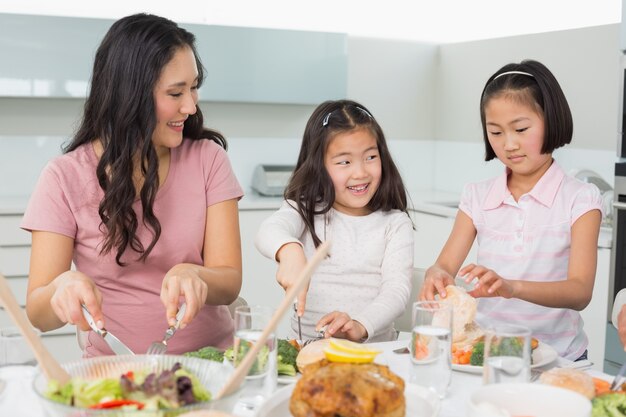 Donna con due bambine che mangiano cibo in cucina