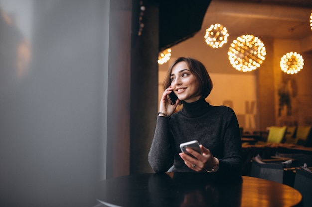 Donna con due telefoni in un caffè