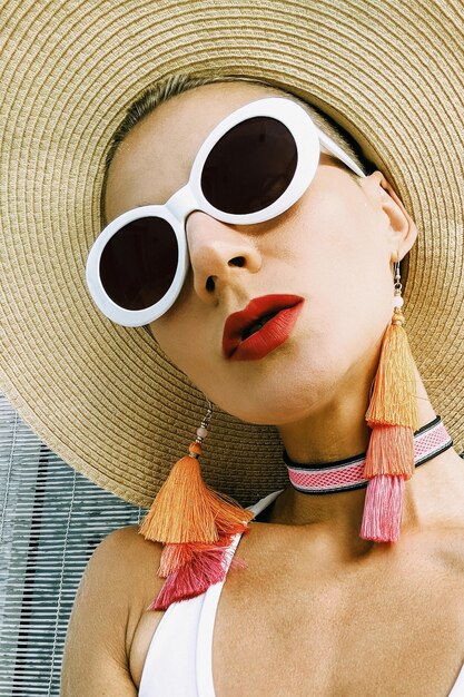 Donna con eleganti accessori da spiaggia occhiali da sole orecchini cappello abbigliamento da spiaggia