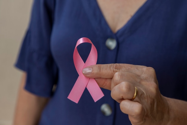 Donna con fiocco rosa in mano. Campagna di prevenzione del cancro al seno. Ottobre rosa