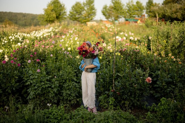 Donna con fiori sulla fattoria di dalia all'aperto