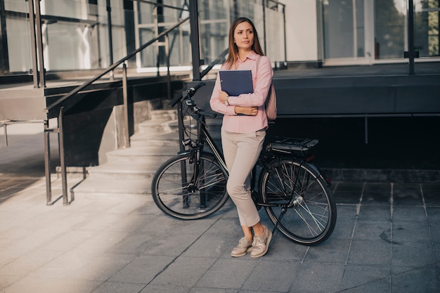 Donna con gli archivi nelle mani che stanno all'aperto davanti alla bici elettrica