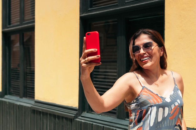 Donna con gli occhiali che cammina per strada e si fa un selfie con il cellulare