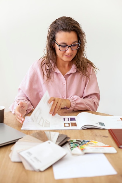 donna con gli occhiali che sfoglia un catalogo al tavolo