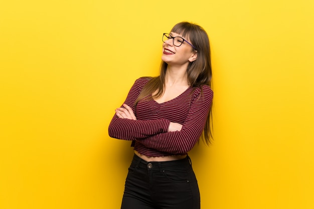 Donna con gli occhiali sul muro giallo Felice e sorridente