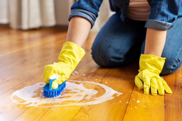 Donna con guanti di gomma sta usando la spazzola per pulire il pavimento concetto di pulizia e pulizia