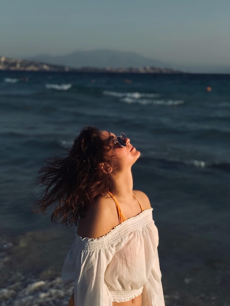 Donna con i capelli disordinati in piedi sulla spiaggia