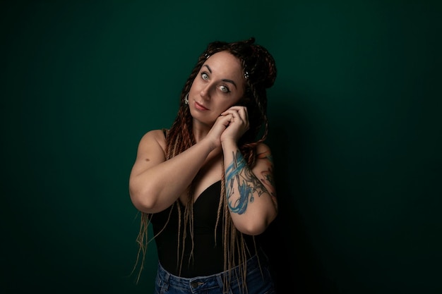 Donna con i dreadlocks appoggiata al muro verde