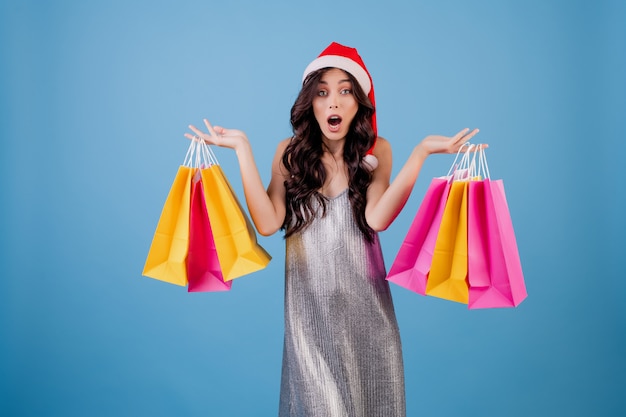 Donna con i sacchetti della spesa variopinti che portano il cappello e il vestito di Santa