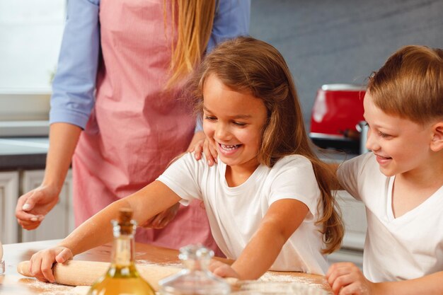 Donna con i suoi bambini che impastano la pasta in cucina