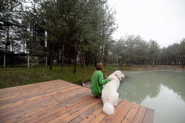 Donna con il cane sul molo vicino al lago nella pineta