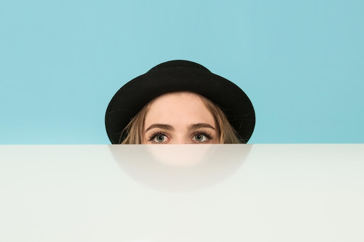 Foto donna con il cappello che guarda dietro il tavolo sullo sfondo blu
