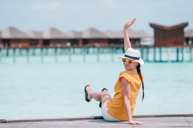 Donna con il cappello giallo che si rilassa alla piscina nella località di soggiorno esotica