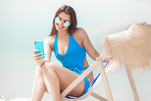 Donna con il cellulare sulla spiaggia in estate Signora che parla al telefono Femmina che fa una foto smartphone