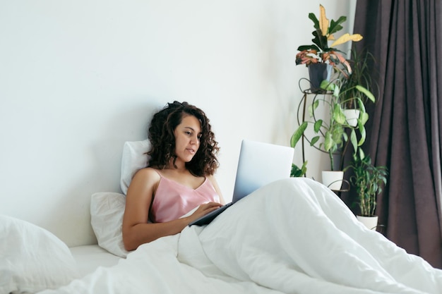 Donna con il computer portatile a letto libero professionista shopping in internet