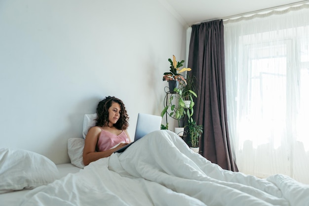 Donna con il computer portatile a letto libero professionista shopping in internet