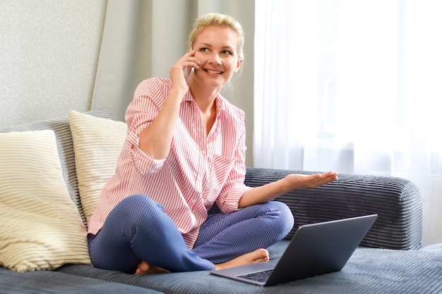 Donna con il computer portatile sul divano a lavorare