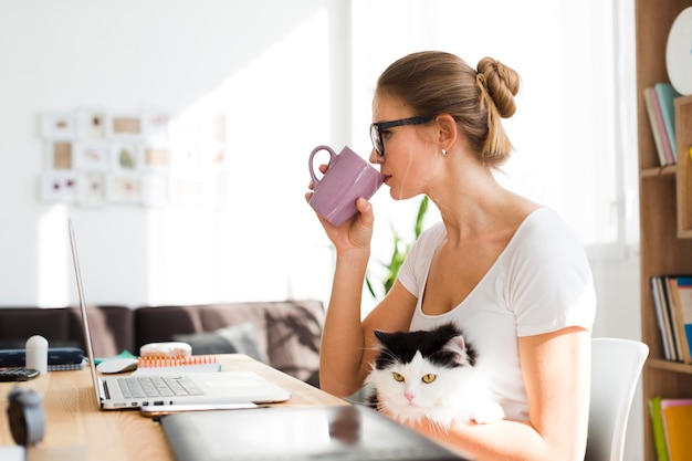 Donna con il gatto allo scrittorio che lavora dalla casa