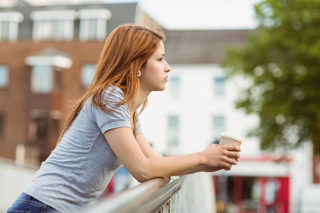 Donna con il giorno della tazza di caffè che sogna sul ponte