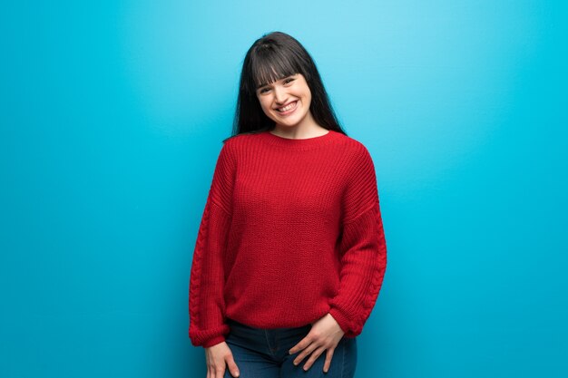 Donna con il maglione rosso sopra sorridere blu della parete