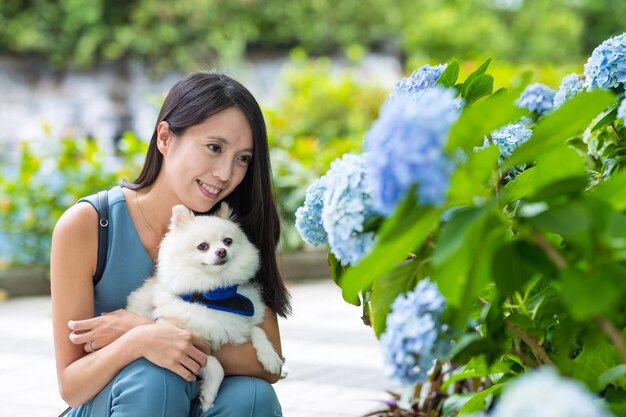 Donna con il suo cane pomeraniano nel giardino dell'ortensia