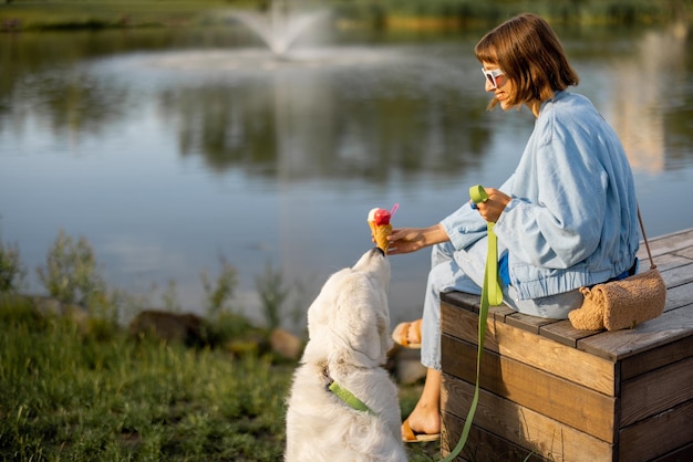 Donna con il suo cane vicino al lago nel parco