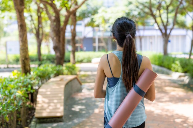 Donna con il suo tappetino da yoga al parco