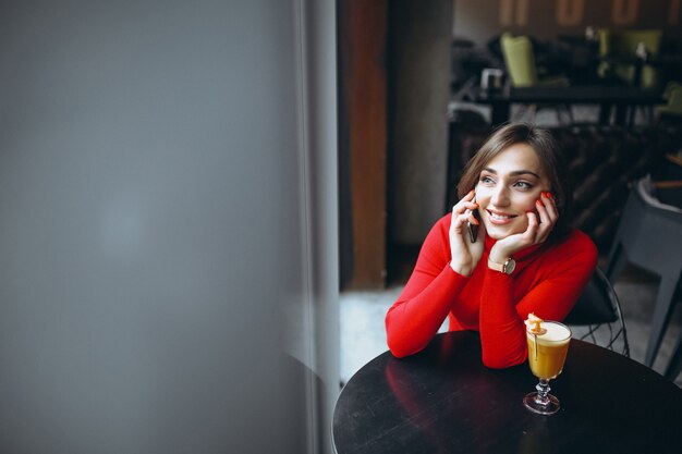 Donna con il telefono che si siede in un caffè