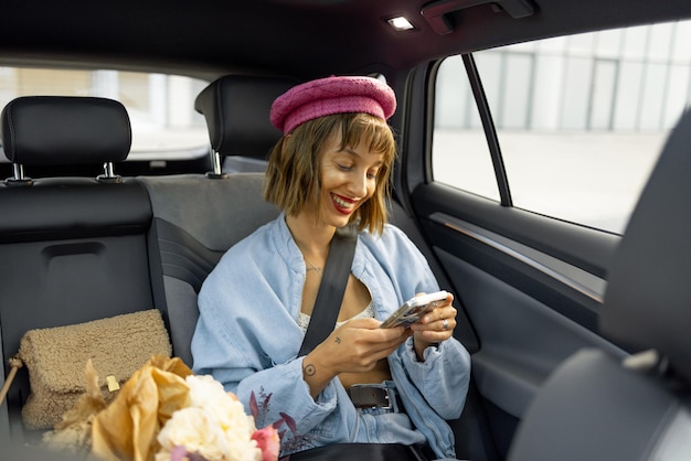 Donna con il telefono sul sedile posteriore di un'auto