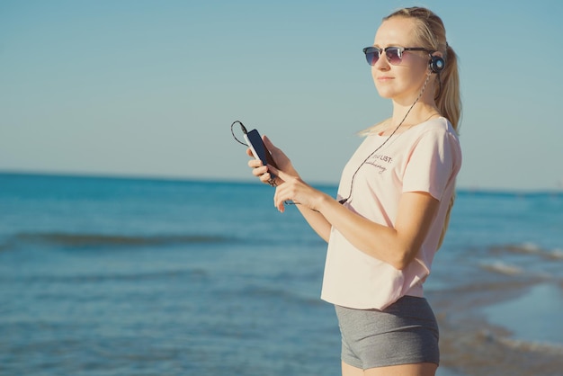 Donna con il telefono sulla spiaggia per rilassarsi e ascoltare musica