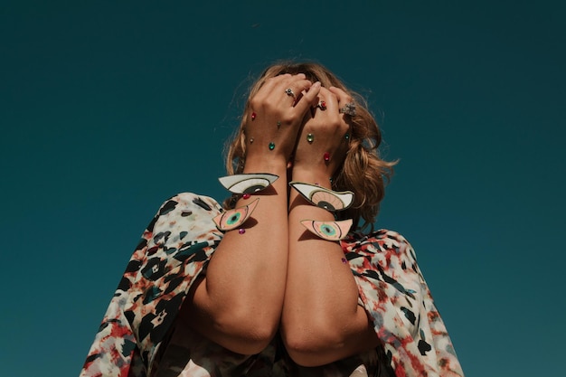 Donna con il trucco che tiene una decorazione in cartone contro un cielo limpido