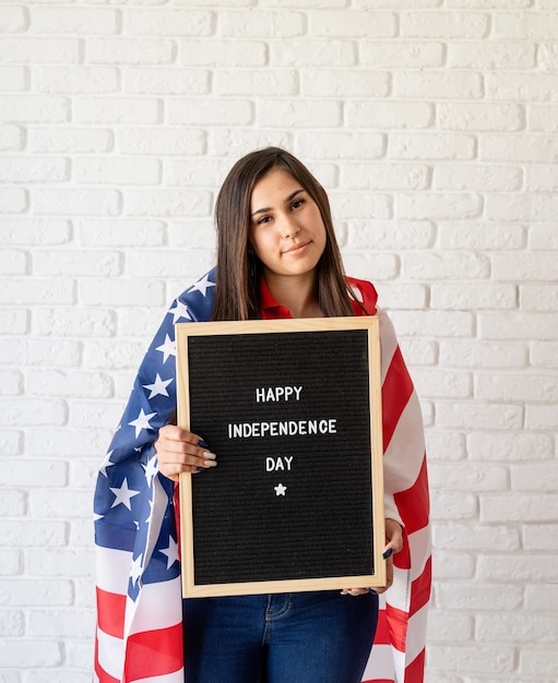 Donna con la bandiera americana che tiene la lavagna con le parole Happy Independence Day