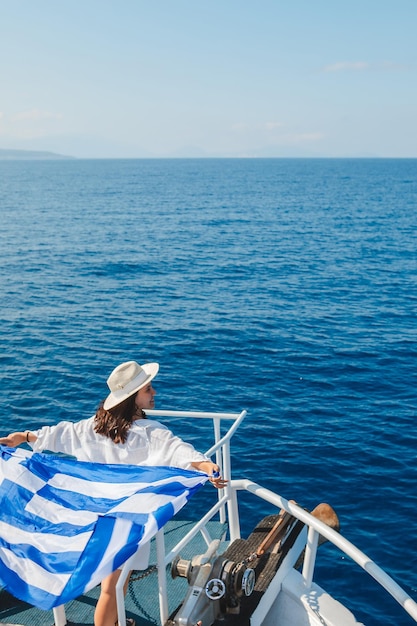 Donna con la bandiera della grecia all'isola di Lefkada in barca da crociera
